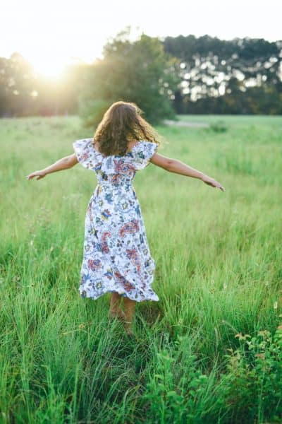 young girl in long dress running through field on Wiccan Beltane